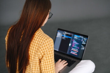 Young woman mobile developer writes program code on a computer, programmer work.