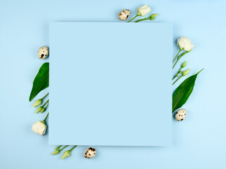 Easter composition. Easter eggs, flowers, paper blank on pastel blue background. White flowers. Flat lay, top view, copy space, mock up.