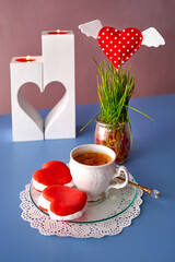 Romantic morning coffee, candles and sweets for Valentine's Day on a blue background. Valentine's Day