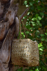 Human hand made dates tree box tool. palm leaf dry jar hanging on wood in garden, brown background culture thing Arabic style picture