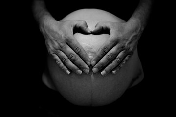 Primer plano  de tripa de embarazada con las manos formando corazón