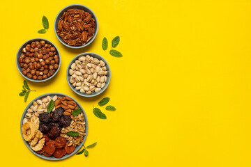 Mixed nuts and dried fruits on a plate on yellow background with copy space. Symbols of the Jewish holiday of Tu Bishvat Healthy snack - mix of organic nuts and dry fruits.
