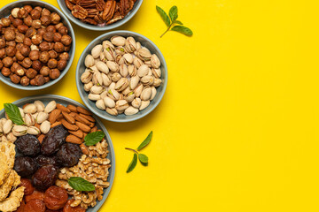 Mixed nuts and dried fruits on a plate on yellow background with copy space. Symbols of the Jewish holiday of Tu Bishvat Healthy snack - mix of organic nuts and dry fruits.