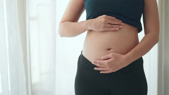 Young pregnant woman touching her belly, she holding baby in pregnant belly, Early pregnancy, Maternity prenatal care and woman pregnancy concept.