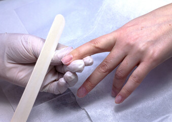 The process of manicure fitting natural nails filing nails coating with colored gel polish and glossy top.