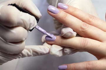 Zelfklevend Fotobehang Het proces van manicure waarbij natuurlijke nagels worden aangebracht, nagels worden gecoat met gekleurde gellak en glanzende bovenkant. © Nataliya