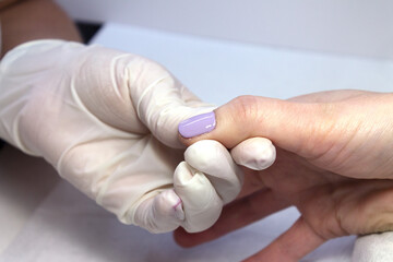 The process of manicure fitting natural nails filing nails coating with colored gel polish and glossy top.