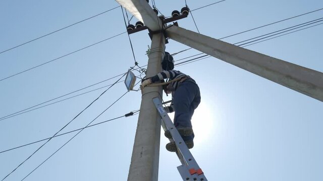 electric silhouette worker engineer working on electric pole standing on stairs