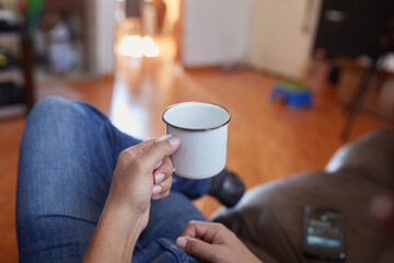 point of view man sitting on his living room couch with a cup of coffee in his hand