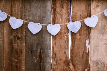garland of purple wooden hearts on dark wooden fence background, valentine's day greeting card