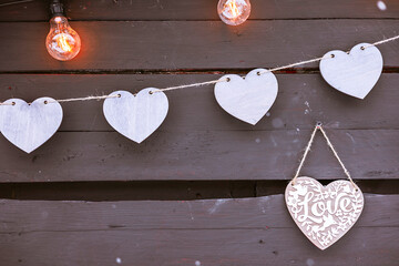garland of purple wooden hearts on dark wooden fence background, valentine's day greeting card