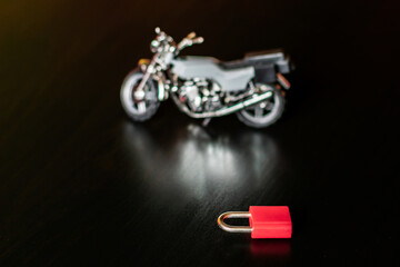 Padlock in the foreground next to an unfocused motorcycle.