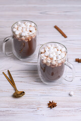 Glass cup of brown cocoa with marshmeloy, on white wooden background