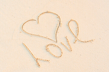 handwritten inscription heart and the word Love on the sand, the concept of travel and greetings for Valentine's Day