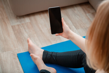 Mockup for app online fitness program, remote yoga class. Woman in sportswear holding Smartphone...
