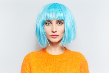 Studio portrait of young beautiful girl with blue eyes and bob haircut, wearing orange sweater on white background.