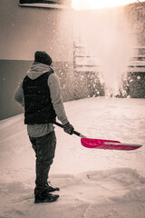 Man is shoveling snow outside in the winter and throwing away the snow up in the air and watch it...