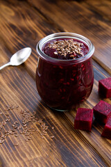 Closeup on beetroot smoothies or puree with flax seeds in the glass jar on the wooden surface