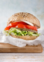 Healthy vegan tofu burger with spinach, lettuce, tomato, onion and fried vegetables