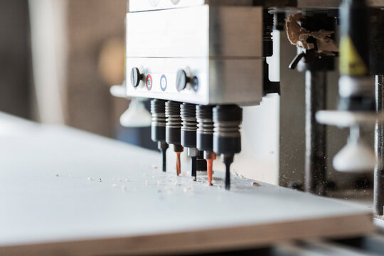 Hinge boring machinery drilling 5 holes in a cabinet door
