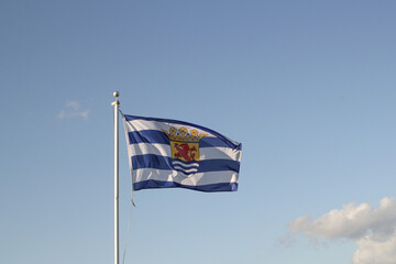 the flag of zeeuws-vlaanderen in the province zeeland in the netherlands with a blue sky in the background in summer
