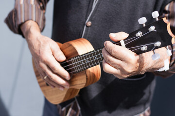 Fototapeta premium Senior person playing soprano ukulele on the street.