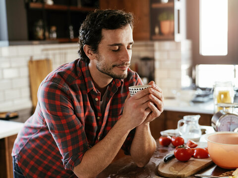 Handsome man preparing breakfast at home. Young man drinking coffee and enjoying in the morning..
