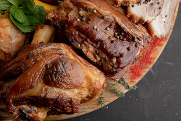A large meat plate. Smoked pork sausages, grilled chicken, beef, pork, on a large plate on a dark background