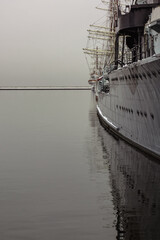 Side shot of a ship moored in port on a cloudy winter day. The colors are faded and the harbor in...
