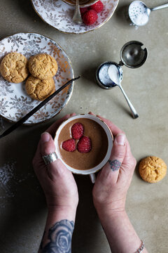 Chocolate mousse. Hands taking a teacup serving of chocolate and raspberry mousse from a table.