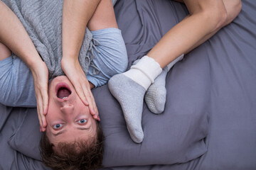Funny married couple lying in bed. Emotion man. Male. Funny photo. Crazy. 