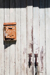 Old wooden door and rusty mailbox. Front view.
