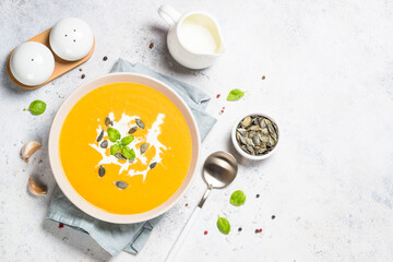 Pumpkin soup with cream. Top view image at white table.
