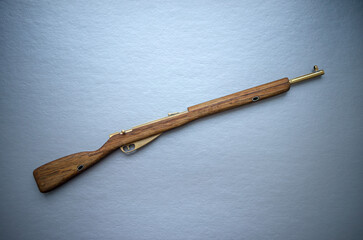 Miniature rifle made of wood with brass on white isolate