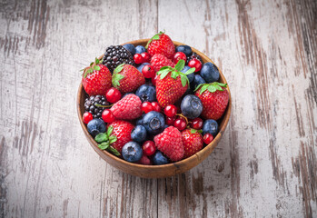 Berries fresh vibrant front view arrangement in wooden jar mix of blackberries, blueberries, strawberries, raspberries and red currant on old white wooden table studio shot