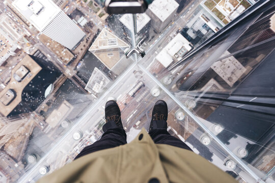First person view of someone looking down through a glass deck up high