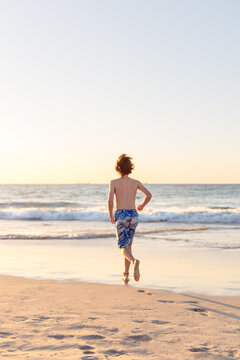 Boy running at the beach at sunset