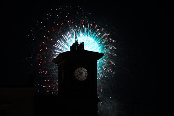fireworks behind a tower with clock from the fascist era. Italy