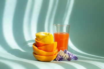 Citrus peel, juice in a glass, flowers and sunshine on a background.