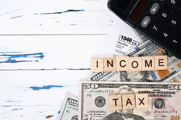 Wooden letters income tax, personal form 1040, dollar bills. Tax payment and filing concept, copy space 