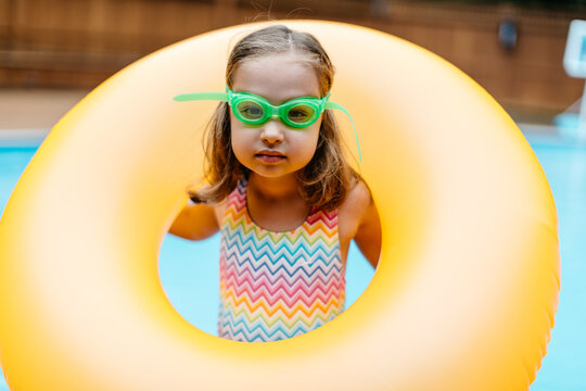 Cute young girl playing with her inner tube by a pool