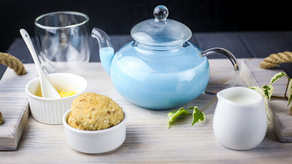 A wooden tray served with blue butterfly tea with milk, honey,cookies
