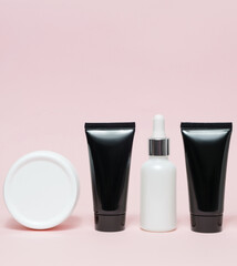 Body moisturizing and revitalizing kit with no inscriptions. Black and white tubes on a pink background.