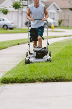 Teenage Boy Mowing The Lawn