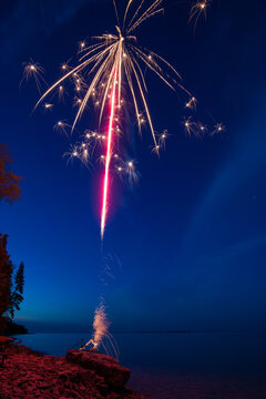 Bright Colorful Fireworks on Rocky Beach At Dusk