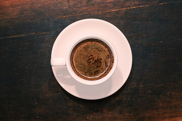 Cup of coffee on brown wooden table. Top view.