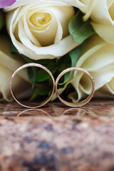 Wedding rings on granite stand against the background of a beautiful bouquet of flowers