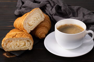 cup of coffee and croissant on wooden table. Top view