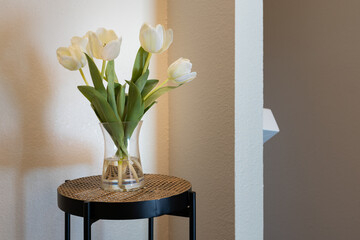 Detail of small table with vase of blooming white tulips. 