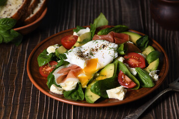 Eggs Benedict (Poached) with Parma ham, slices of avocado, tomato and tender spinach leaves,...